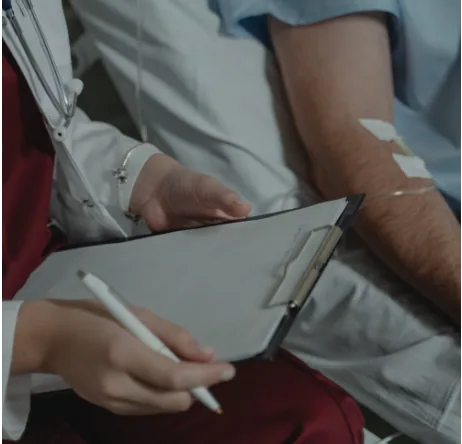 A clinician reviewing notes beside an awake patient